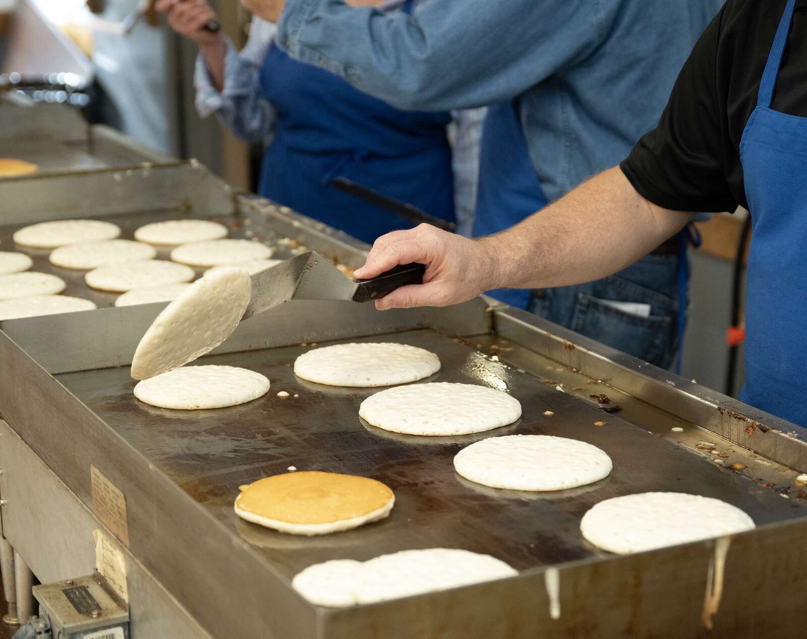 A steady flow of pancakes sizzle on the griddle