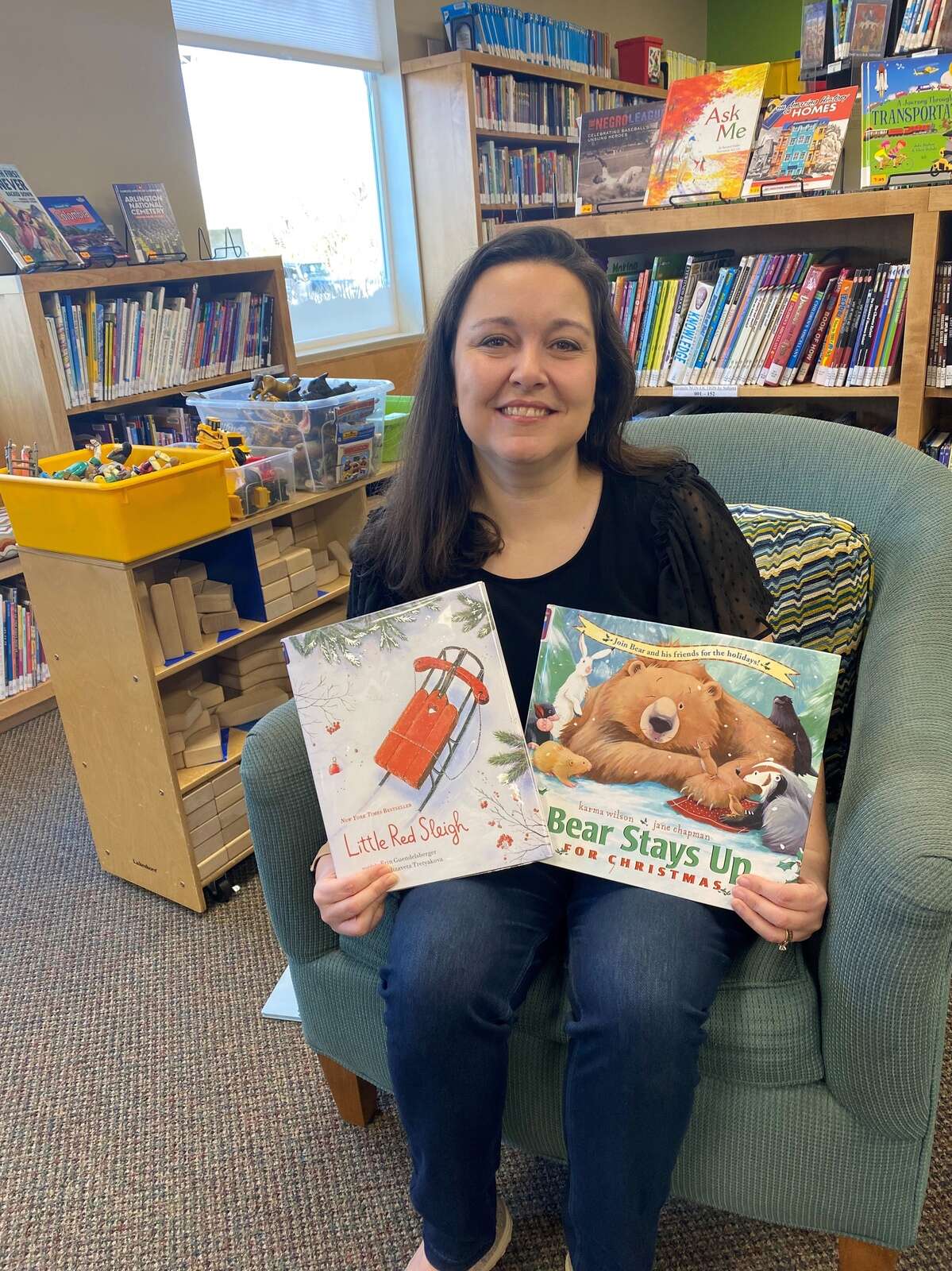 Bridget Weleski, youth services leader at South Butler Community Library, holds up two favorite Christmas books