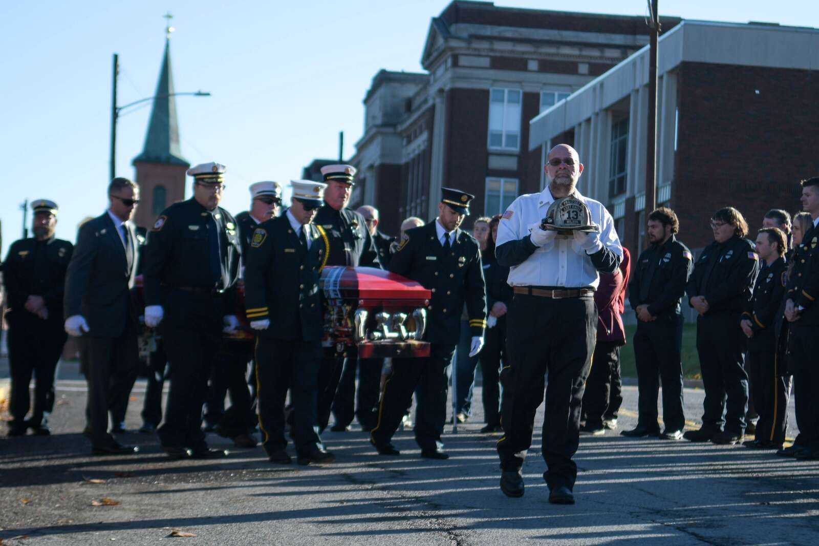 Frank Wilson carries his brother's helmet as he leads pallbearers to the firetruck