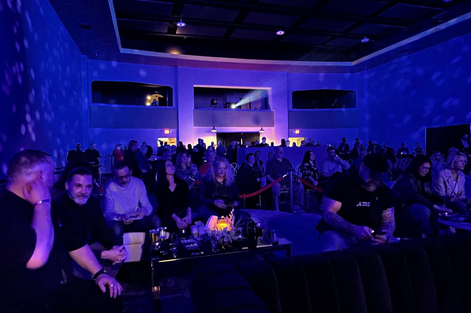 The crowd sits under a projector during a private event celebrating the revitalization of the Penn Theater